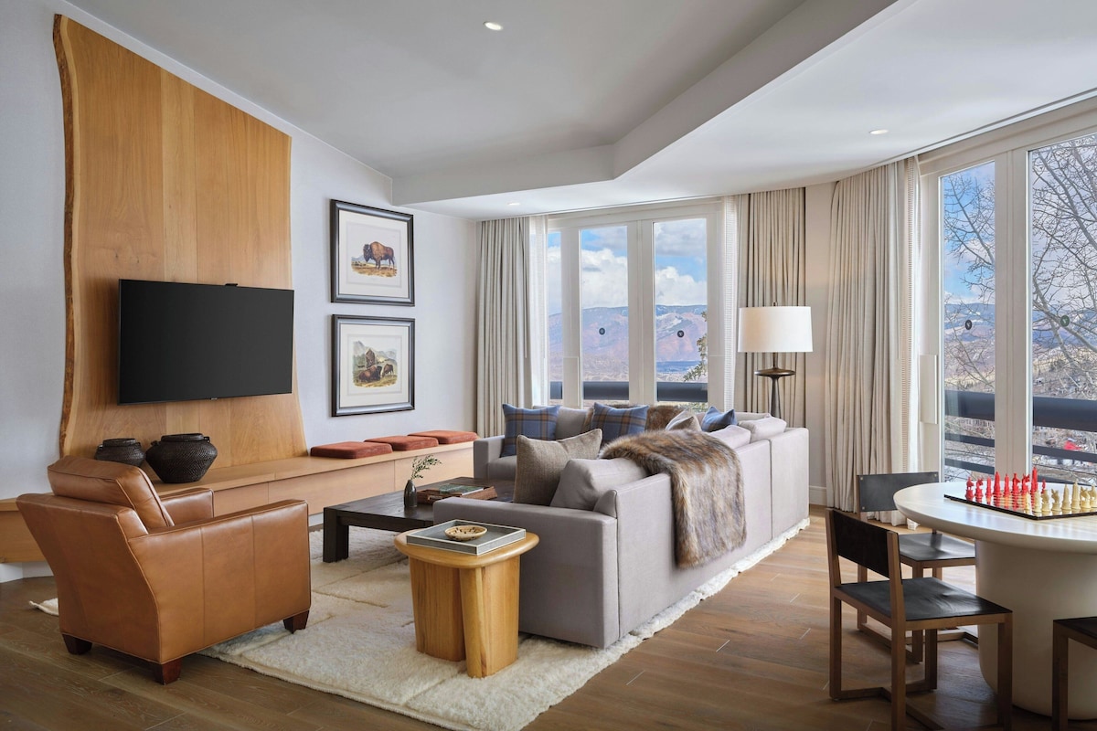 A modern living room with a flat-screen TV, a sofa, a coffee table, and a chessboard.