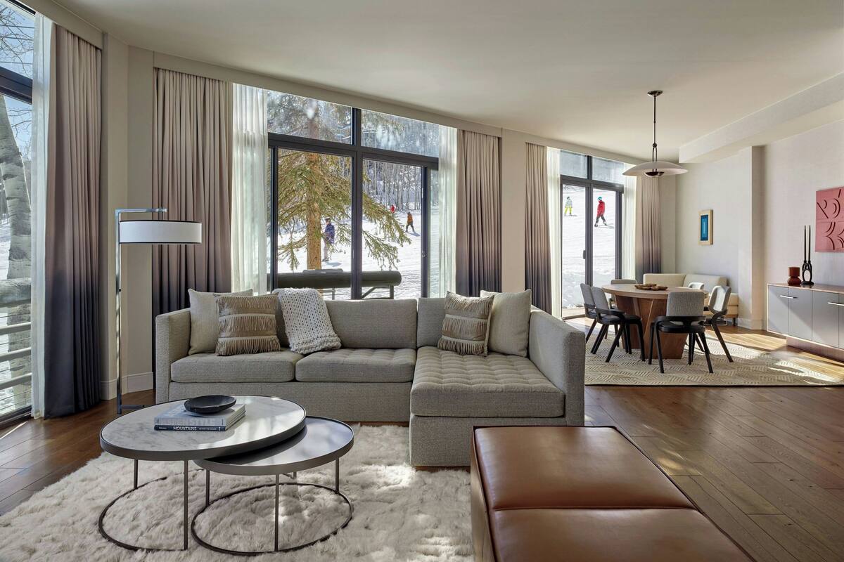 Un salon moderne avec un canapé d’angle, une table basse ronde et un coin repas comprenant une table et des chaises.