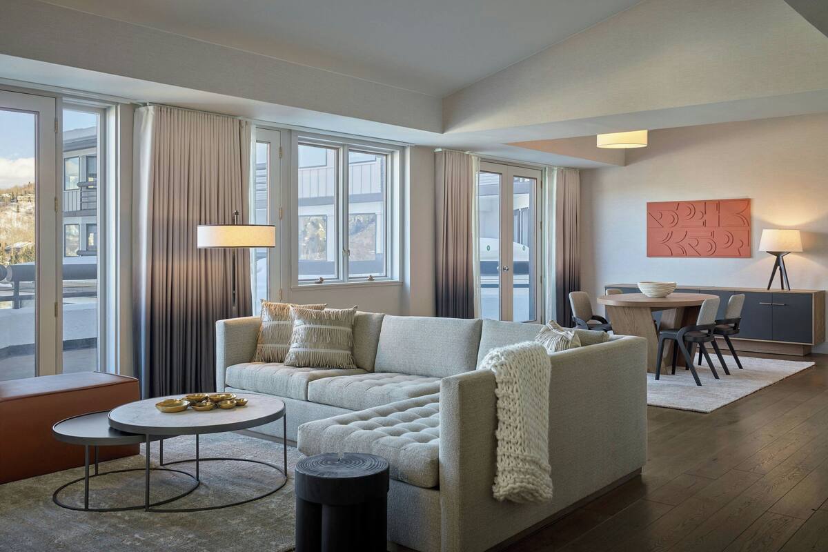 Un salon moderne comprenant un canapé, une table basse ronde et un coin repas avec une table et des chaises.