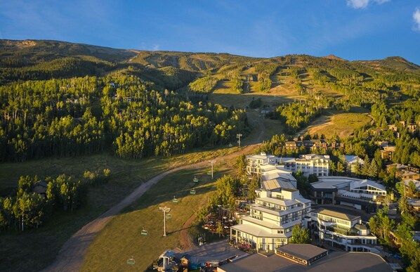 A resort with multiple buildings, a ski lift, and a forested mountain backdrop. - Viewline Resort Snowmass, Autograph Collection (Snowmass Village)