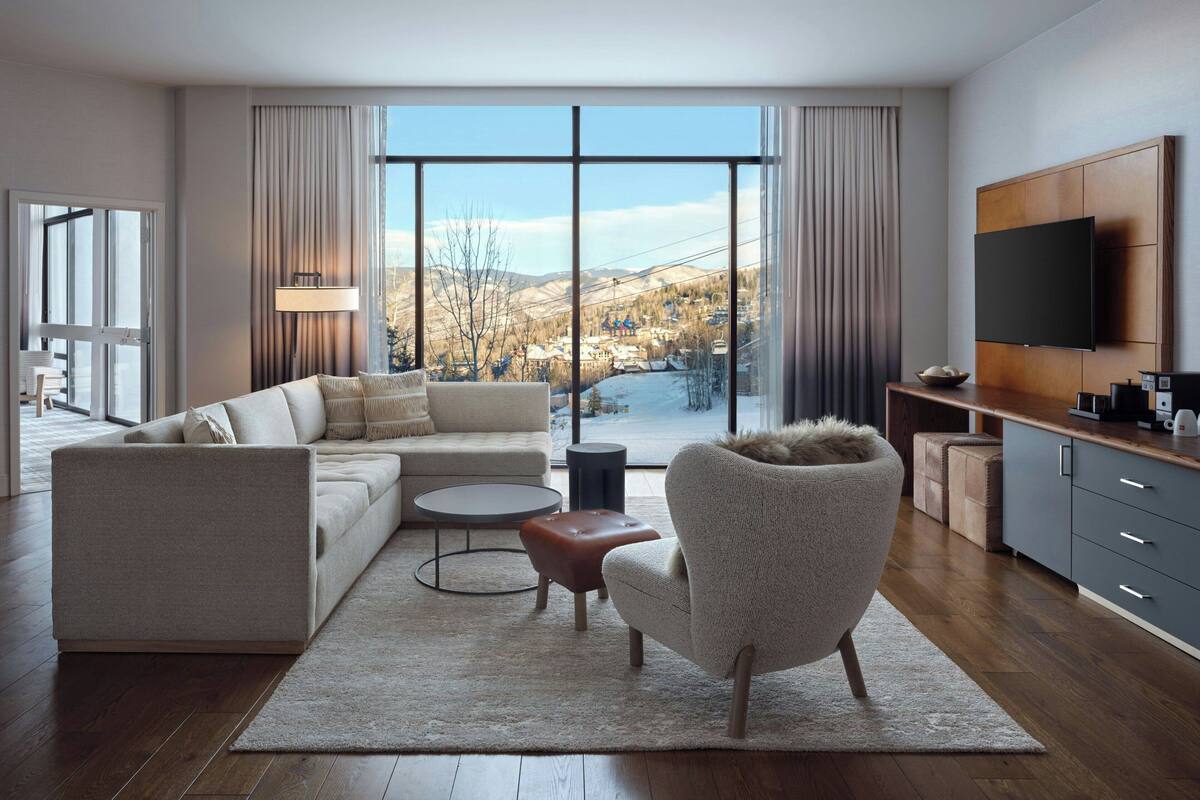 Un salon moderne comprenant un canapé, un fauteuil, une table basse et un téléviseur fixé au mur.