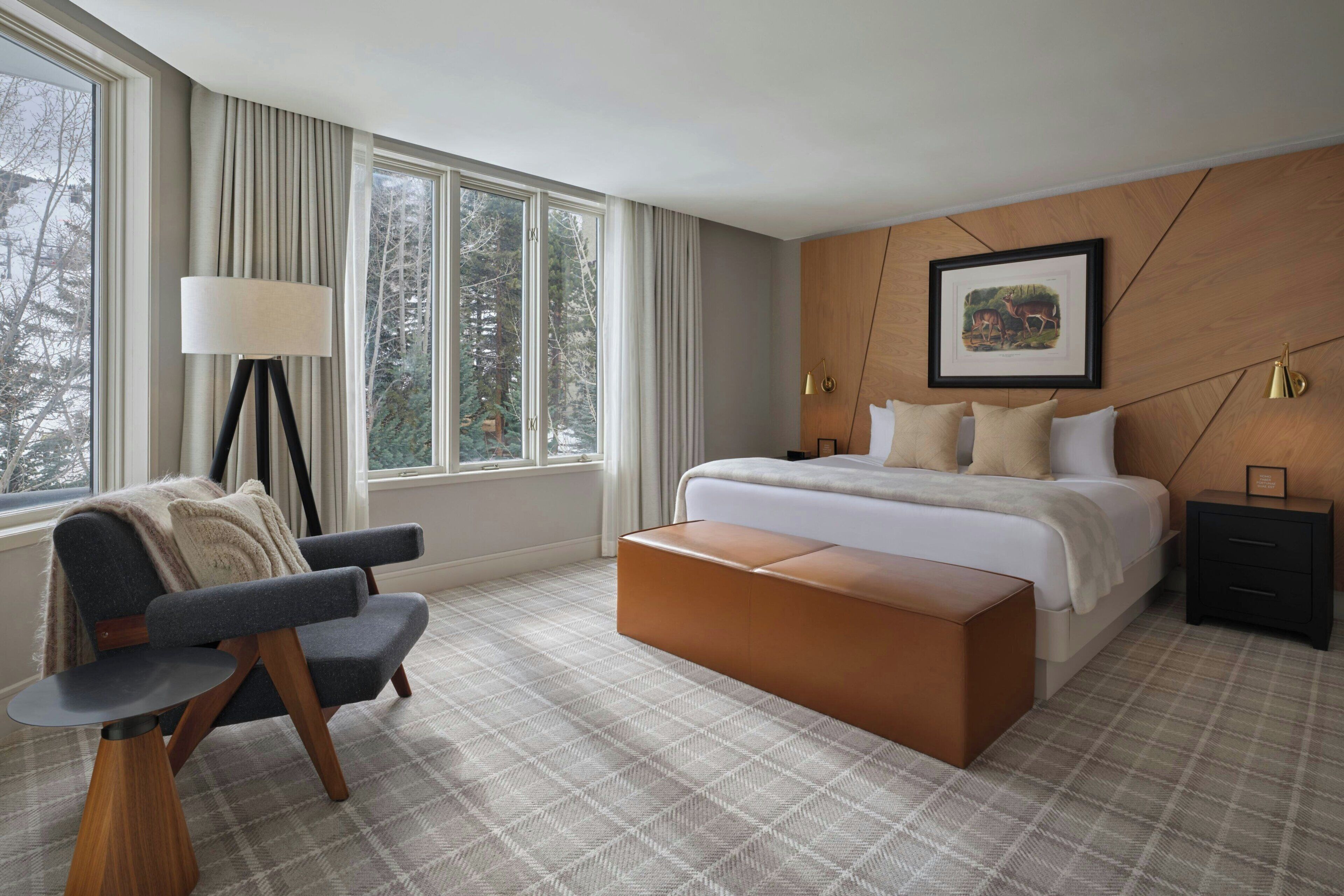 A bedroom with a bed, bedside tables, a chair, a floor lamp, and a window with curtains.