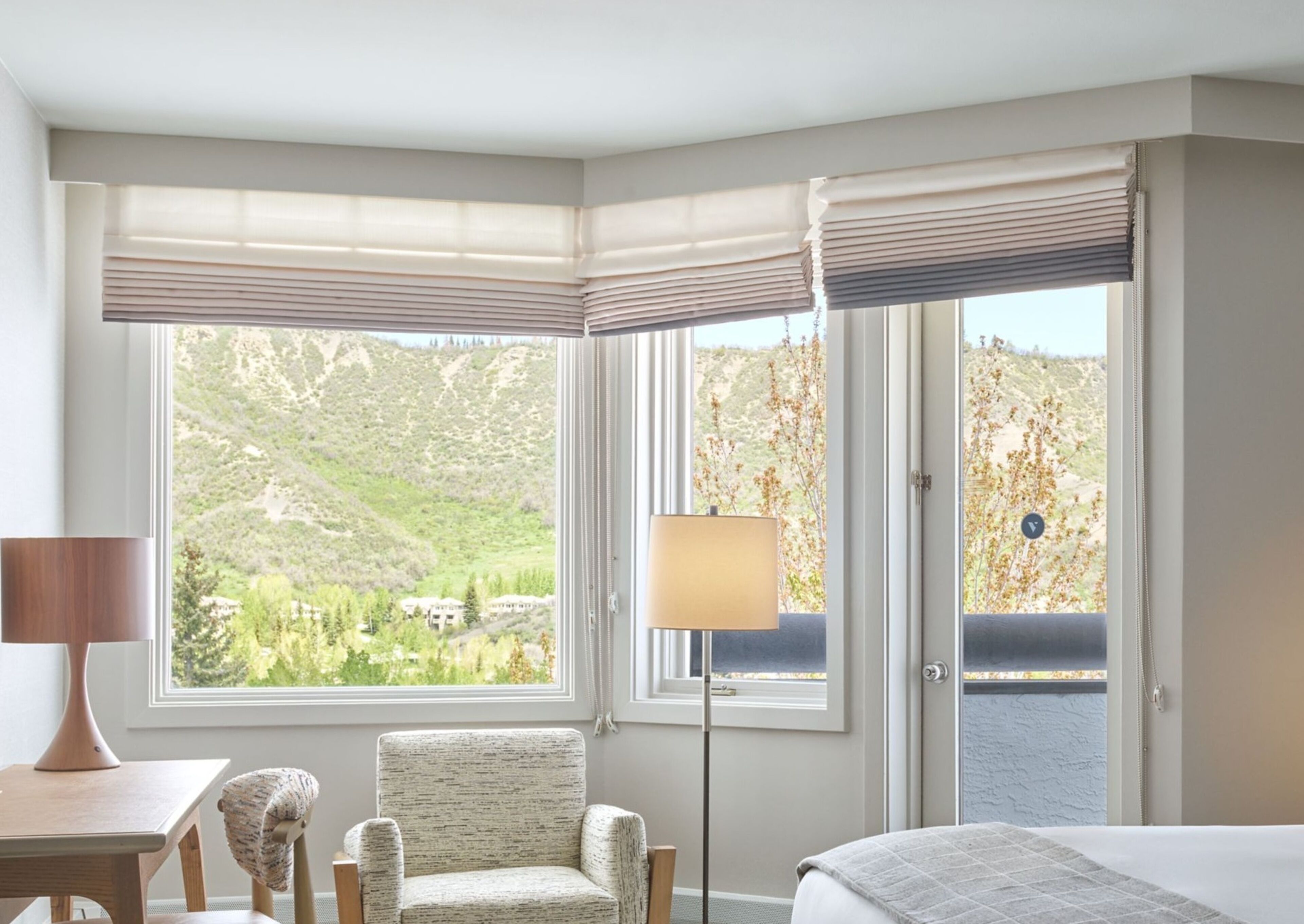 A hotel room with a large window offering a view of a mountainous landscape.