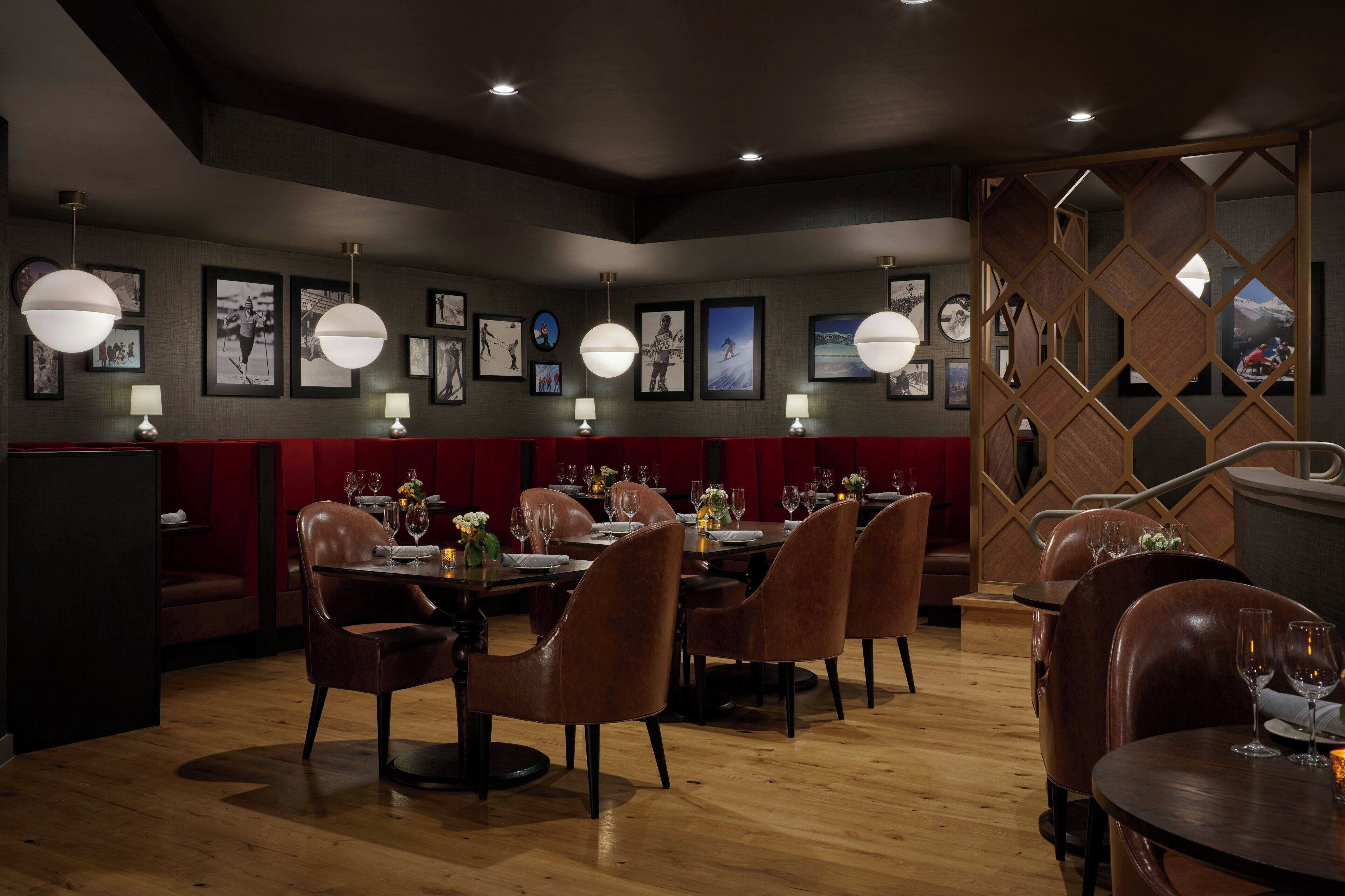 Ein Restaurant mit Holztischen und -stühlen, gerahmten Bildern an den Wänden und Pendelleuchten.