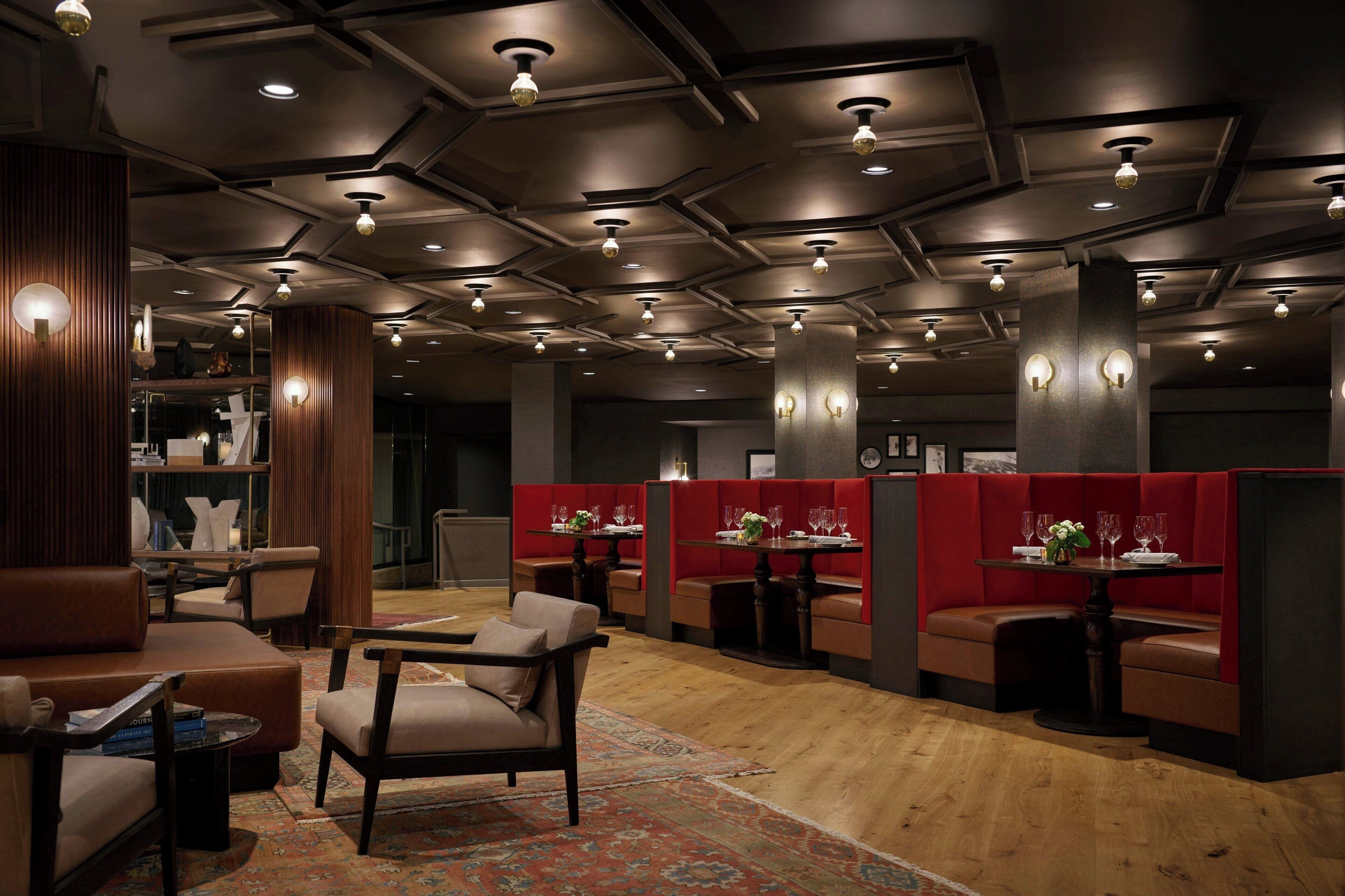 A modern interior with wooden flooring, leather seating, and tables set for dining.