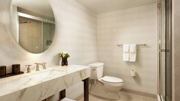 A modern bathroom with a marble vanity, a toilet, and a glass shower enclosure.