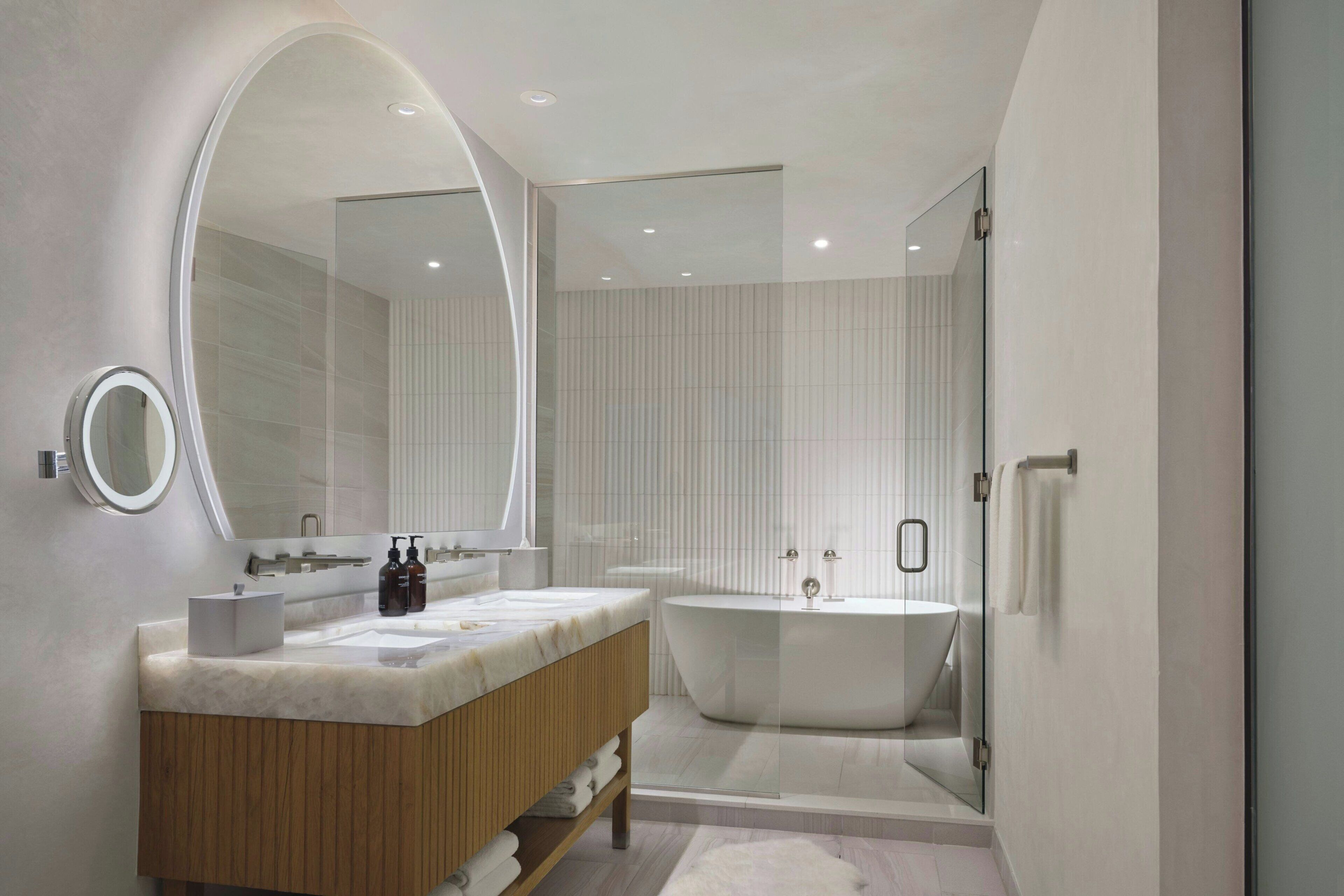 A modern bathroom with a freestanding tub, a vanity with a mirror, and a glass-enclosed shower area.