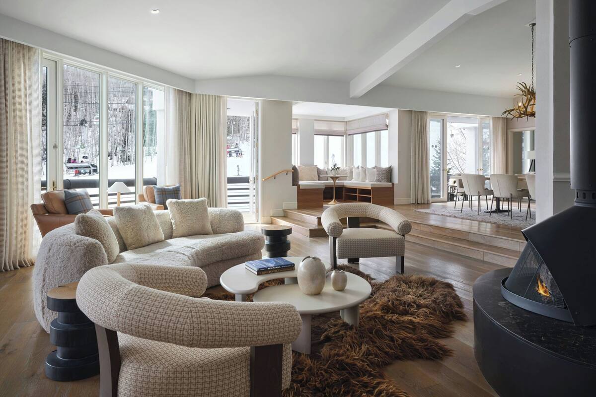 Un salon moderne avec un canapé d’angle, une cheminée et une vue sur l’extérieur.
