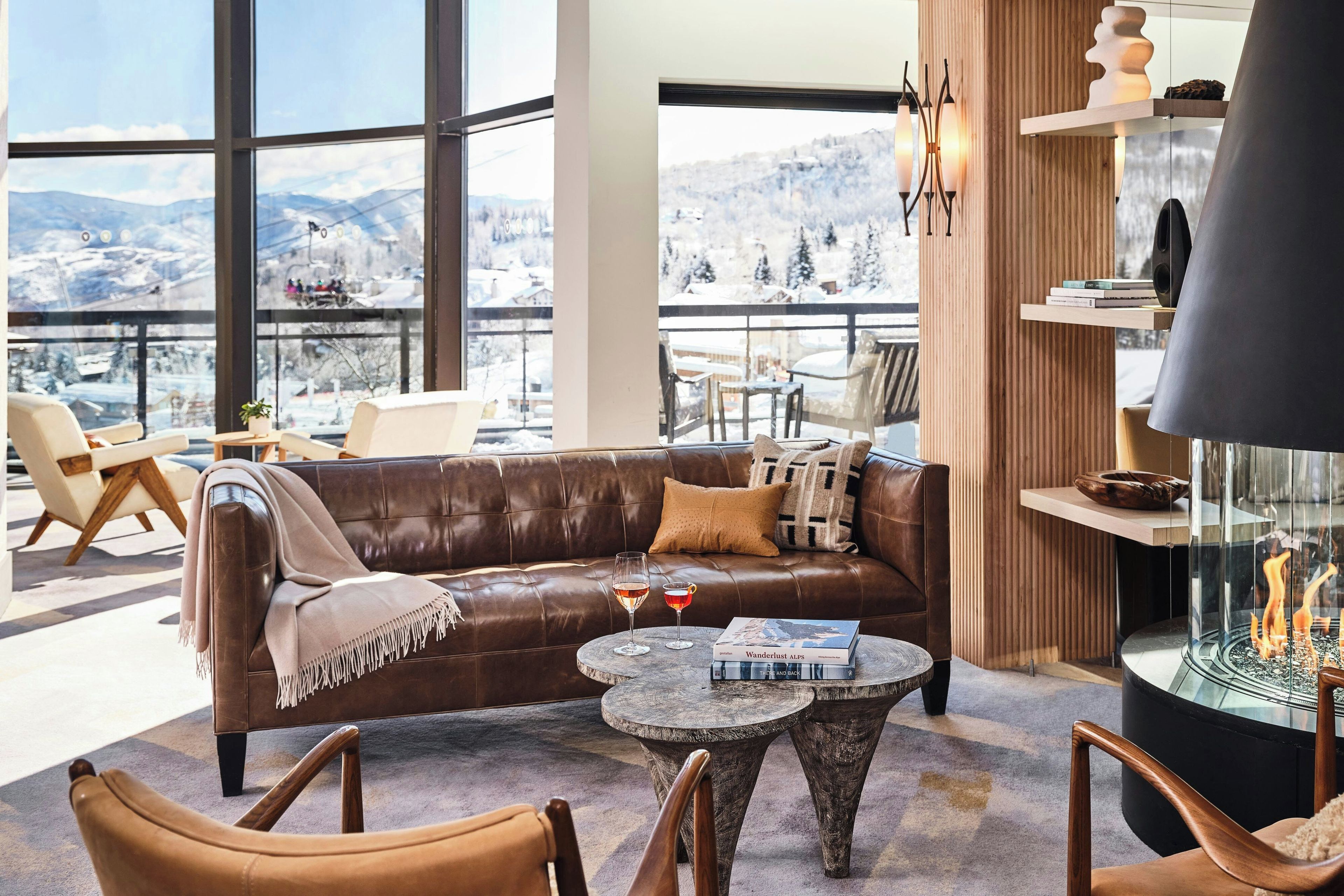 A modern lounge area with a leather sofa, round tables, and a fireplace.