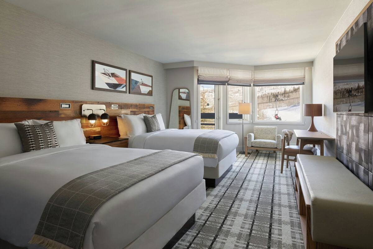 Une chambre d’hôtel avec deux lits, un bureau, une chaise et un téléviseur.