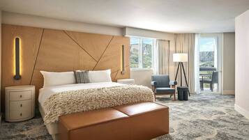 Un cuarto de hotel con una cama grande, un cabecero de madera, vistas al exterior, una silla y una lámpara.