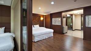 Habitación de hotel con una cama grande, zona de estar independiente, baño y mostrador de recepción.