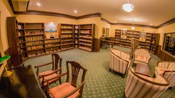 A library with bookshelves, reading chairs, and a green patterned carpet.