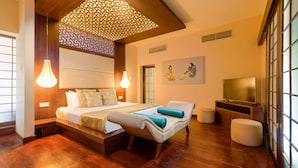 A hotel room with a wooden floor, a bed with pillows, a bedside table, a wall-mounted TV, and a decorative ceiling panel. - Hunas Falls Hotel (Ukuwela)