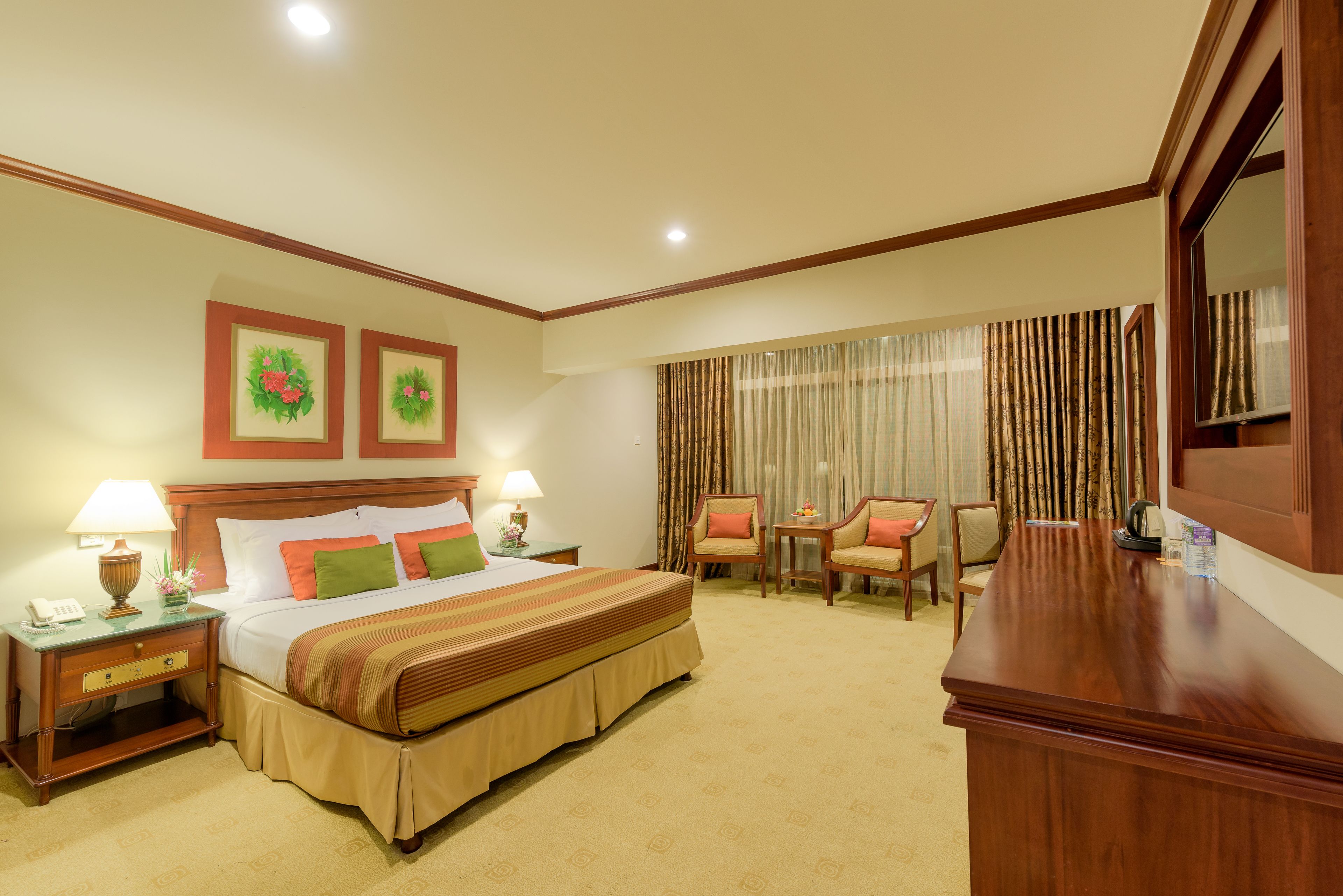 Una habitación de hotel con una cama grande, dos mesitas de noche con lámparas, un escritorio y una silla.