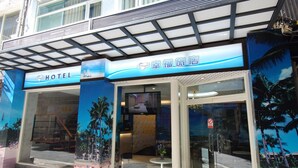 A hotel entrance with a tropical theme, including palm trees and a beach scene. - Happiness Inn (Taipei)