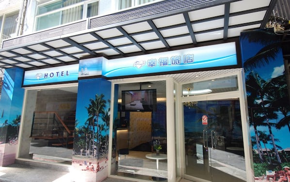 A hotel entrance with a tropical theme, including palm trees and a beach scene.