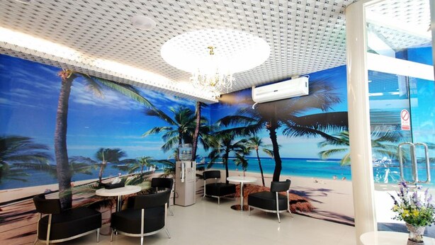 A room with a beach mural, a chandelier, and a seating area with black chairs and a white table. - Happiness Inn (Taipei)