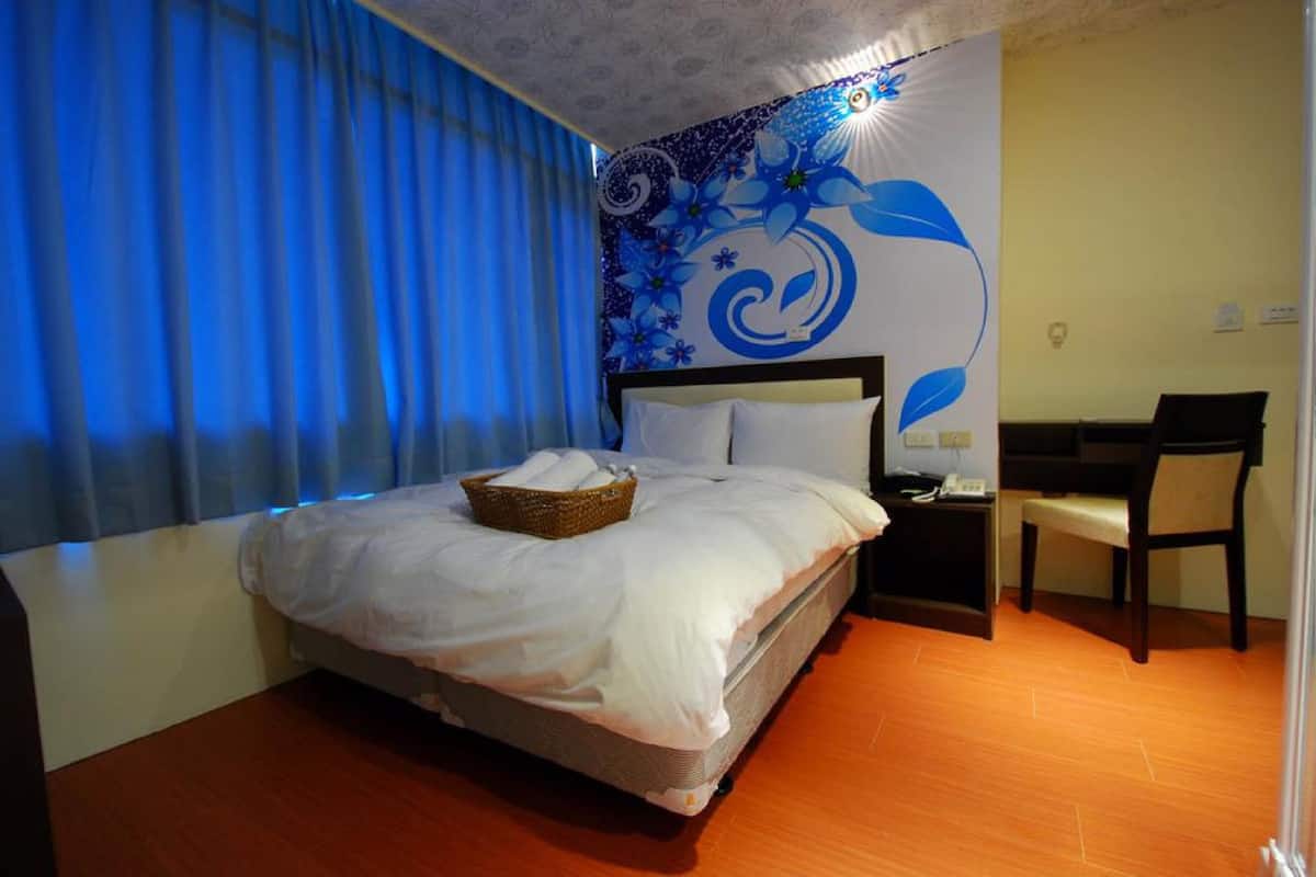 A hotel room with a bed, a desk, and a chair.