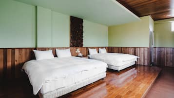A room with two beds, wooden flooring, and a wooden wall panel.