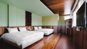 Una habitación con dos camas, suelo de madera y techo de madera.
