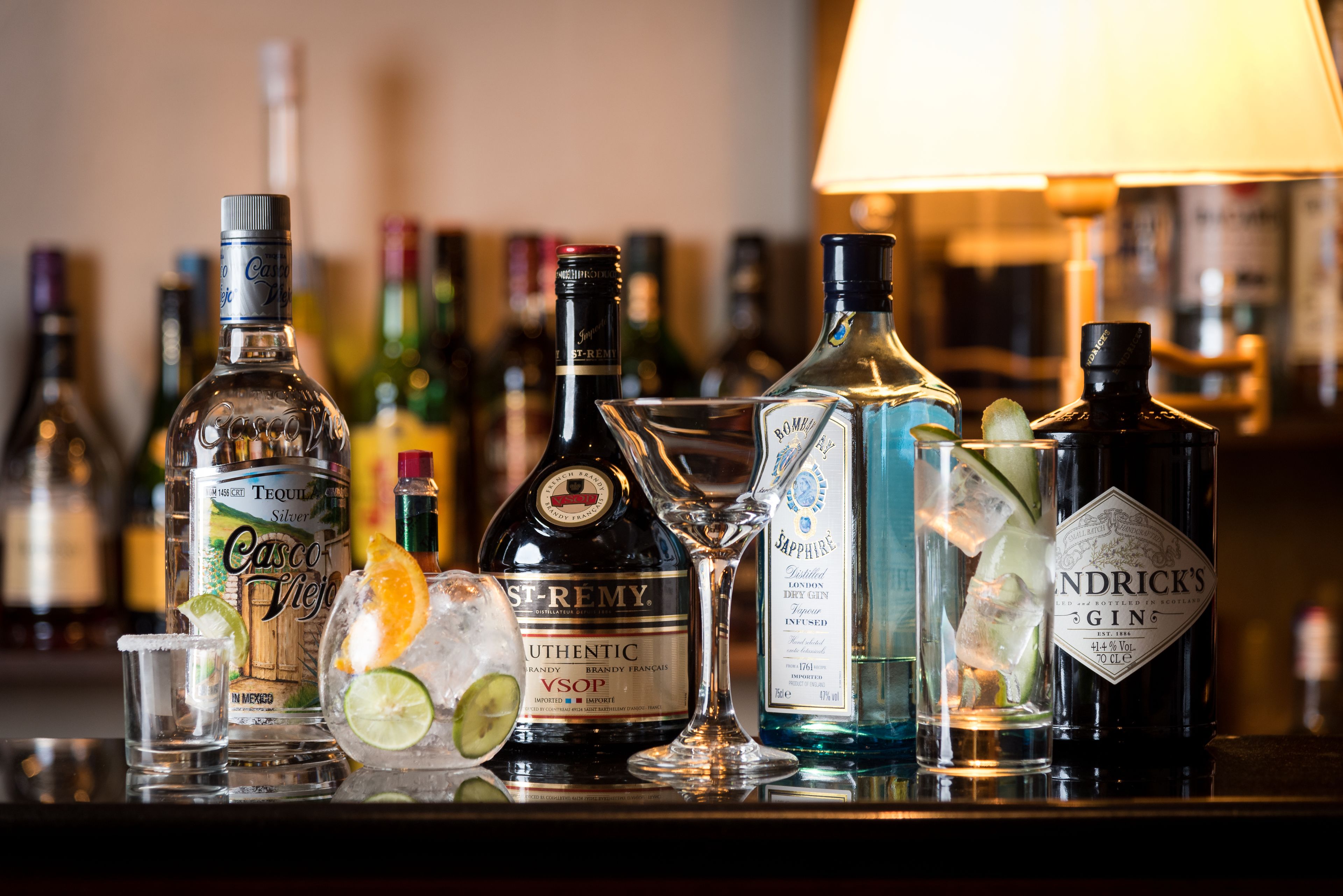 A bar with various bottles of alcohol, a glass pitcher, and a shot glass.