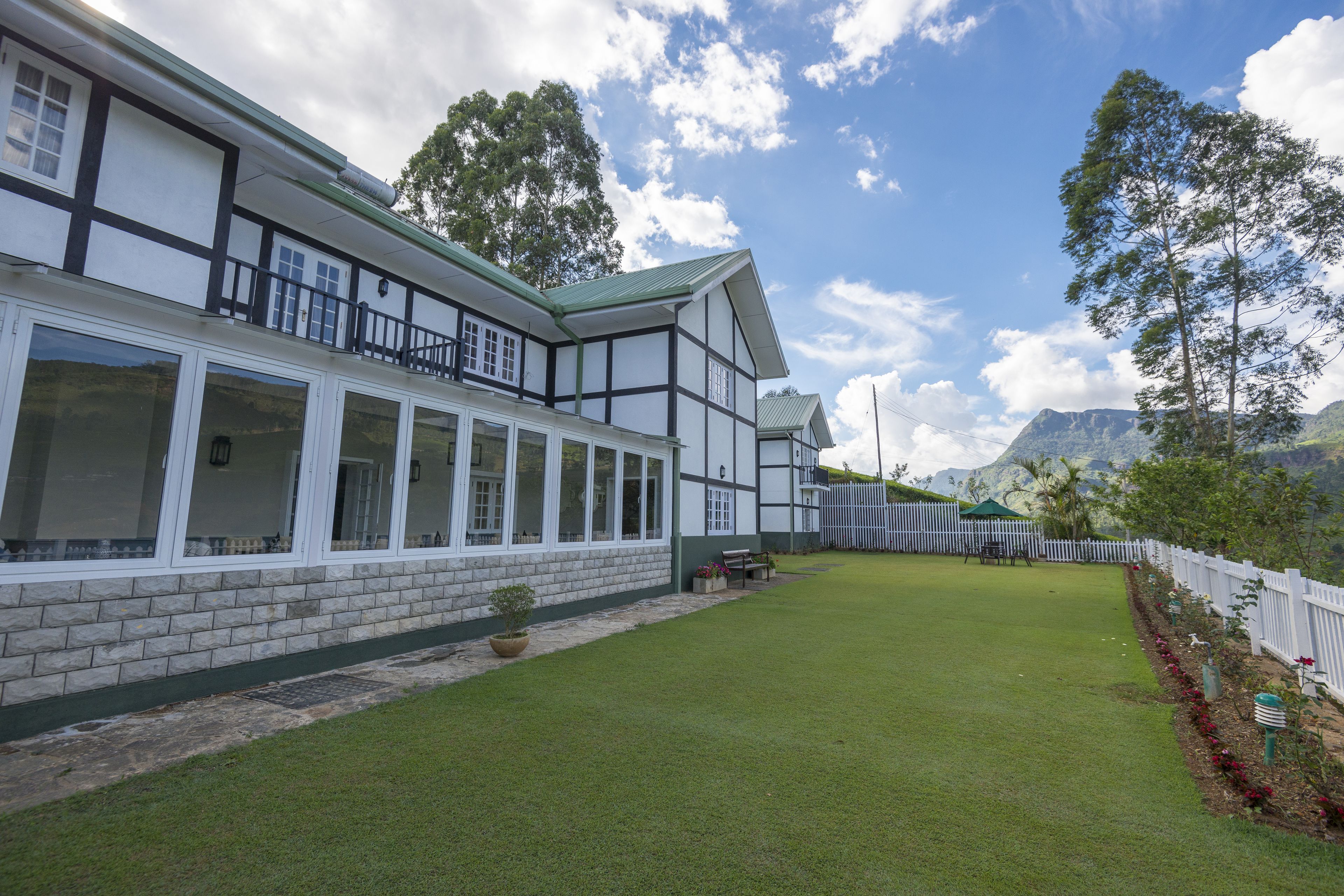 A two-story building with a white facade and dark trim, a green roof, and a well-maintained lawn.