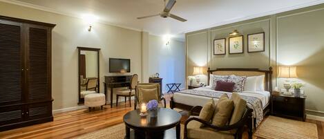 A bedroom with a bed, bedside table, lamp, chair, desk, television, and wardrobe.