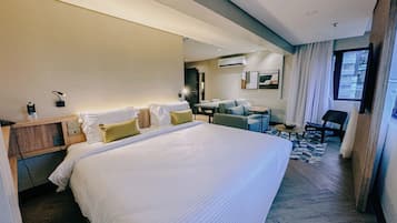 A modern hotel room with a large bed, a desk, and a seating area.