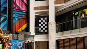 Um hall amplo com design moderno, apresentando um sofá laranja grande, uma escultura de madeira e uma pintura abstrata colorida.