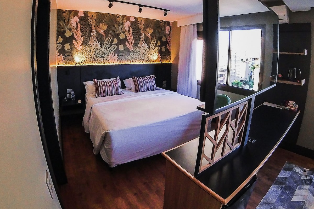 Un dormitorio moderno con una cama grande, un televisor y una decoración de pared.