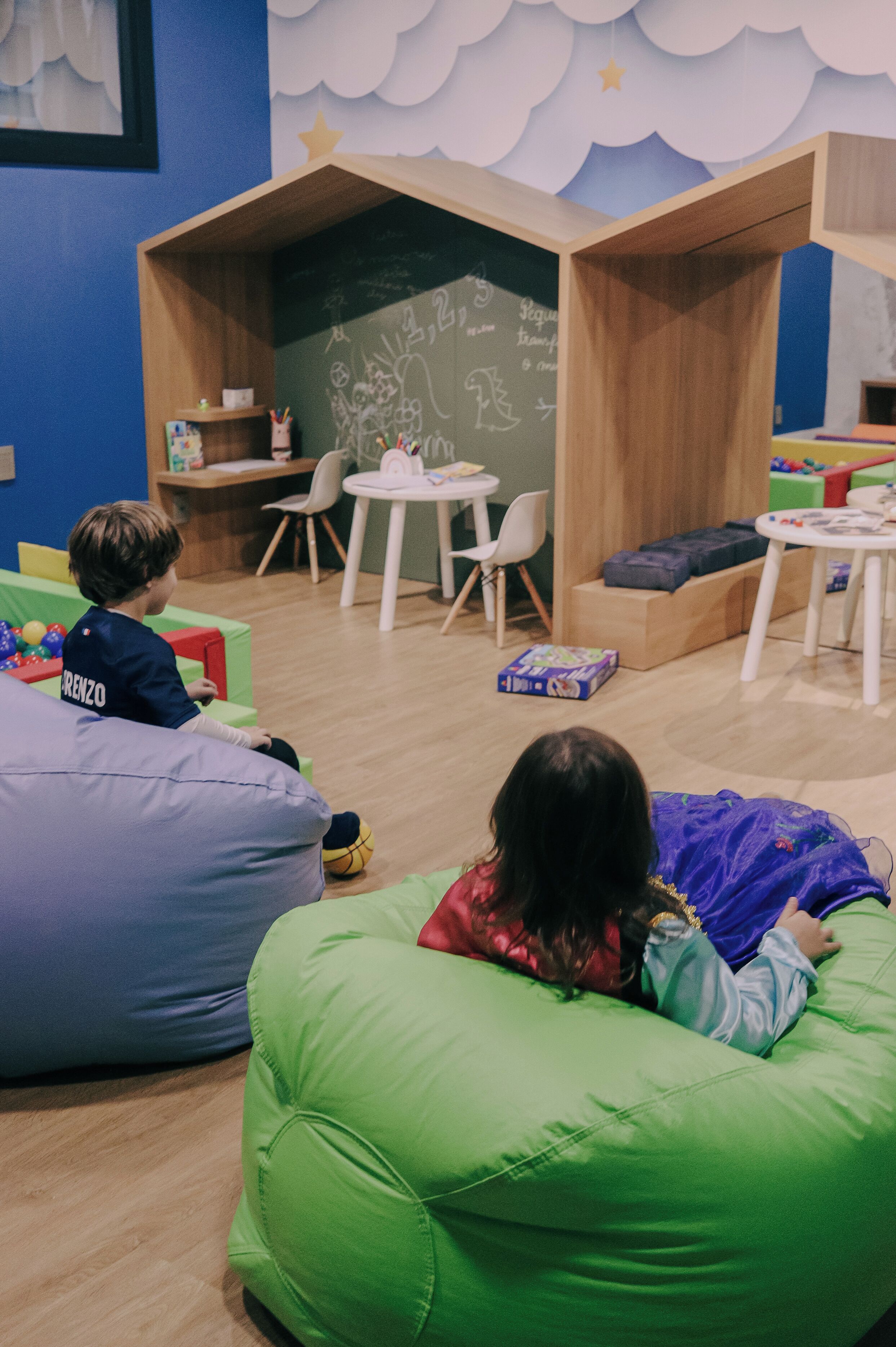 Een kinderspeelruimte met zitzakken, tafels en lesmateriaal.