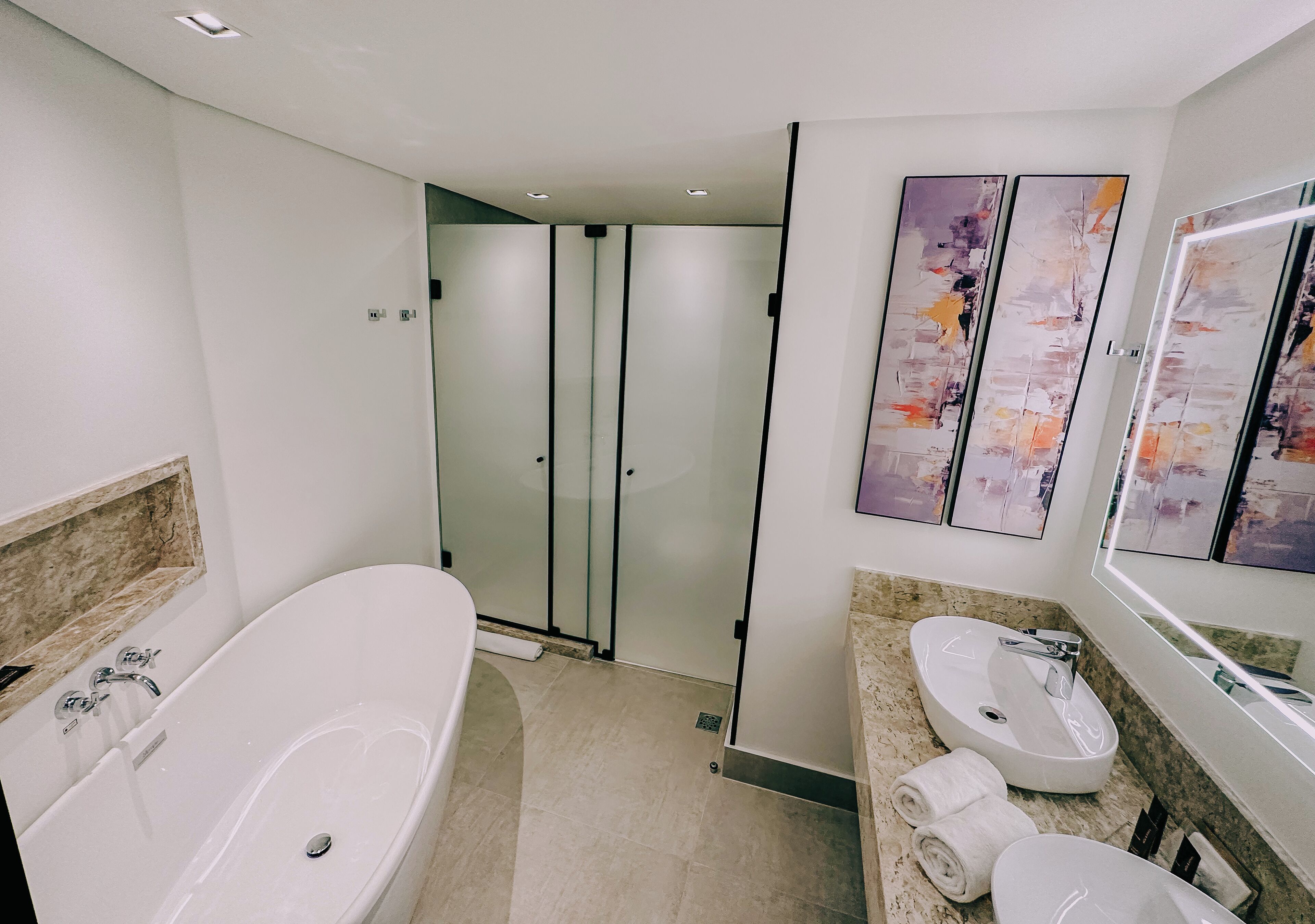 Une salle de bain moderne avec une baignoire sur pieds, une douche à parois de verre et un meuble-lavabo avec un évier et un miroir.