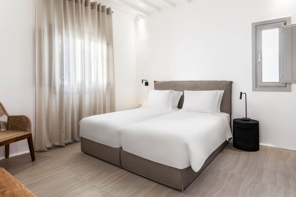 Una cama doble con cabecera de madera, una mesita de noche, una lámpara y una silla.