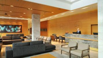 A modern lobby with a reception desk, seating area, and a large abstract painting.