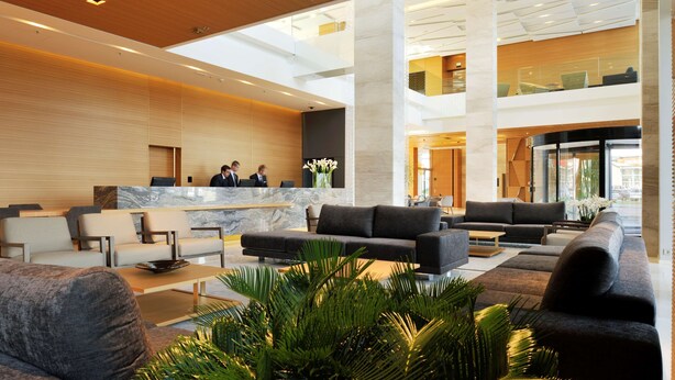 A spacious lobby with a reception desk, seating area, and a high ceiling with natural light. - Radisson Blu Plaza Hotel Ljubljana (Ljubljana)
