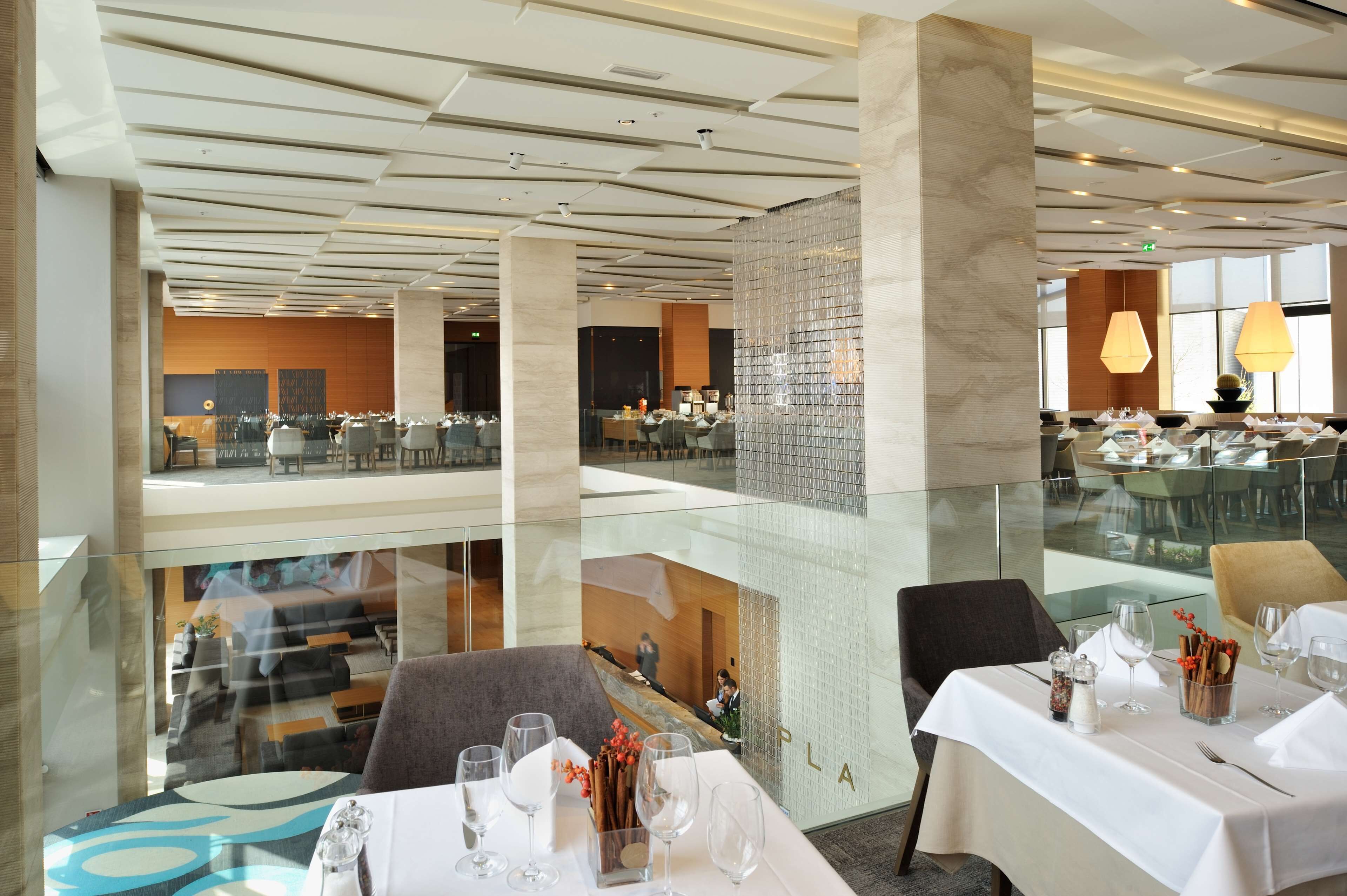 A modern restaurant with glass railings, high ceilings, and a spacious layout.