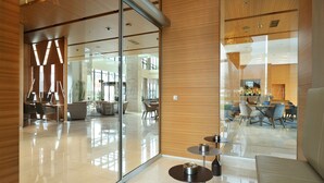 A modern interior with glass partitions, a dining area with round tables, and a seating area with sofas. - Radisson Blu Plaza Hotel Ljubljana (Ljubljana)
