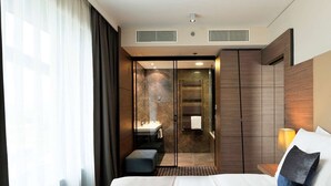 A modern hotel room with a large bed, a separate bathroom with a glass door, and a view of the city. - Radisson Blu Plaza Hotel Ljubljana (Ljubljana)