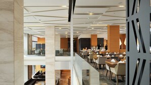 A modern hotel lobby with a glass railing, a staircase, and a dining area with tables and chairs. - Radisson Blu Plaza Hotel Ljubljana (Ljubljana)