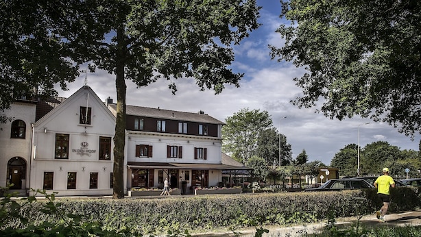 A white building with a sign reading "Hotel In Den Hof."