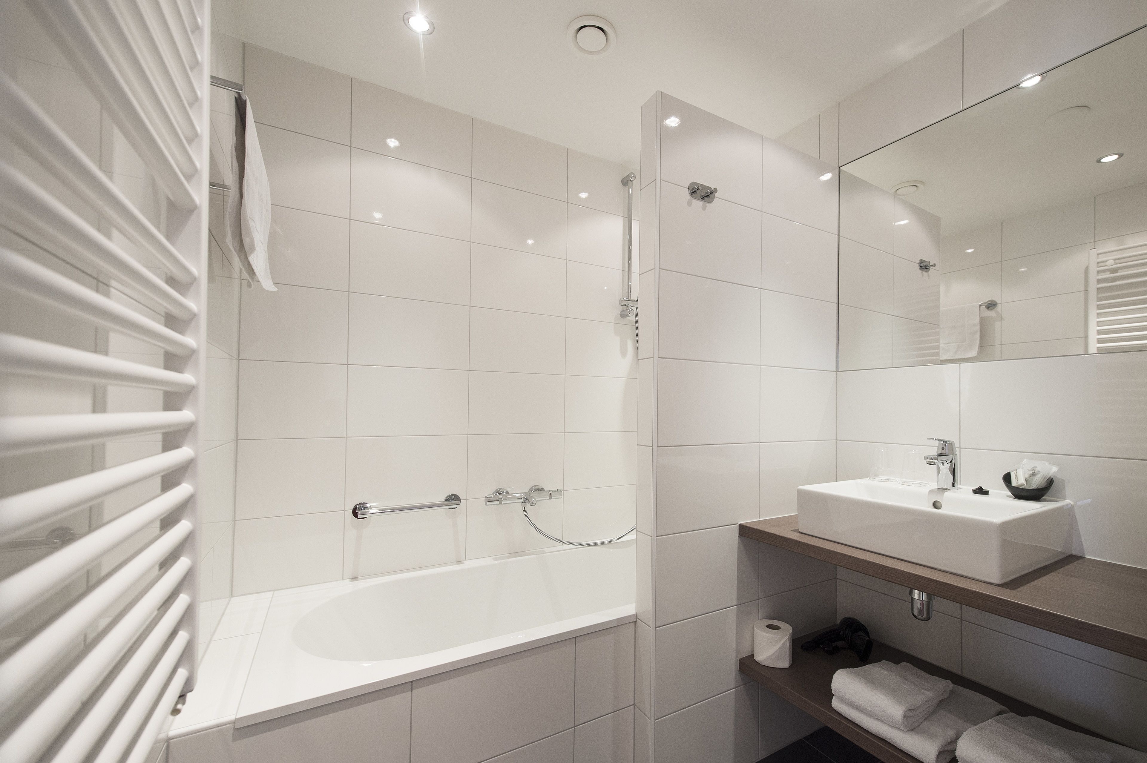 A modern bathroom with a bathtub, a sink, and a mirror.