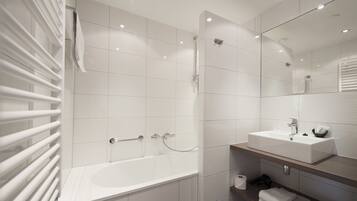 A modern bathroom with a bathtub, a sink, and a mirror.
