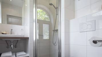 Un baño moderno con ducha envuelta en vidrio, un lavamanos blanco y un inodoro.