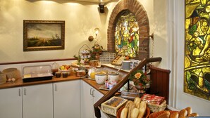 A breakfast buffet with various food items, a stained glass window, and a painting on the wall.