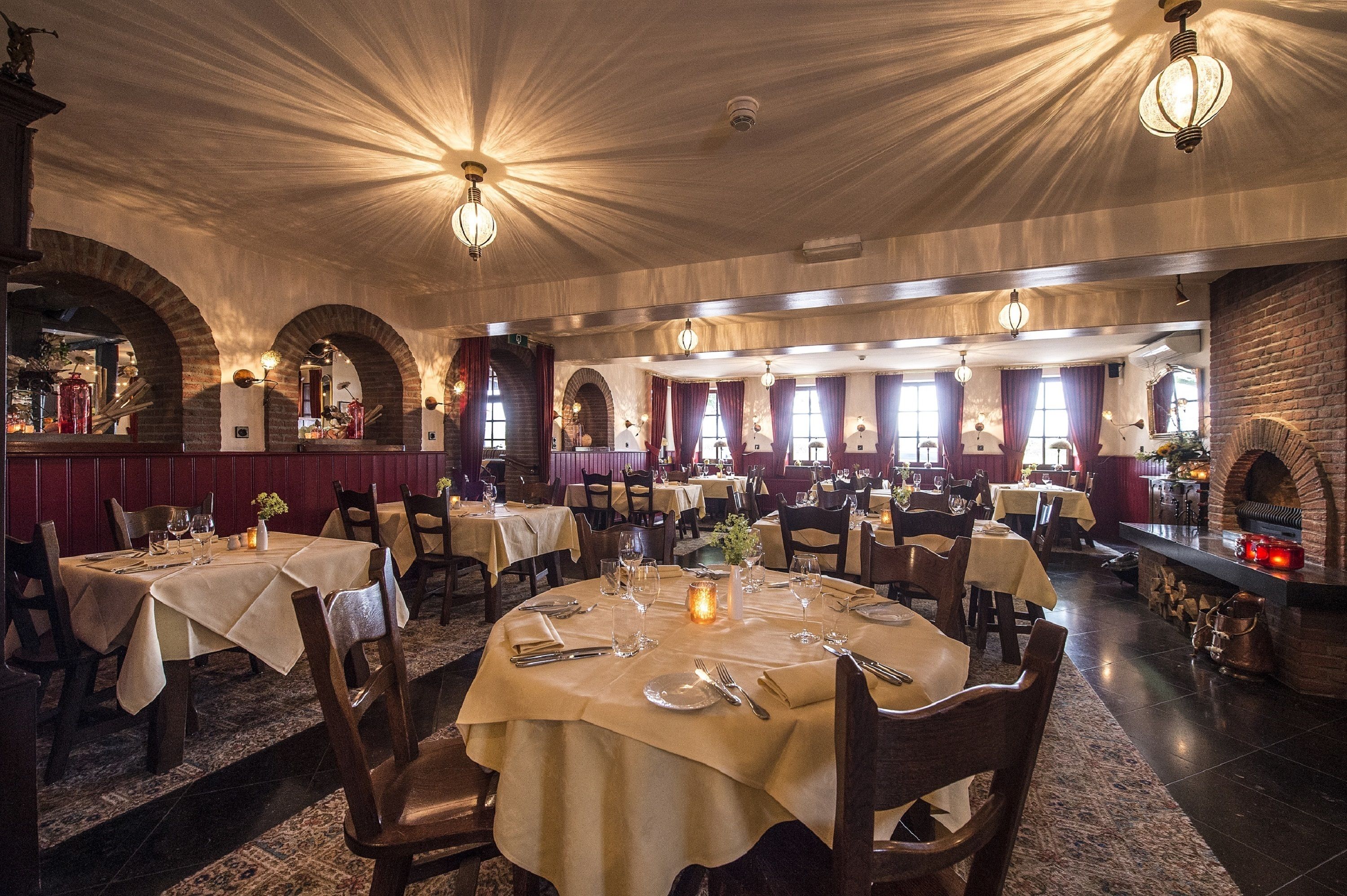 Un restaurante con mesas redondas, candelabros y paredes de ladrillo.