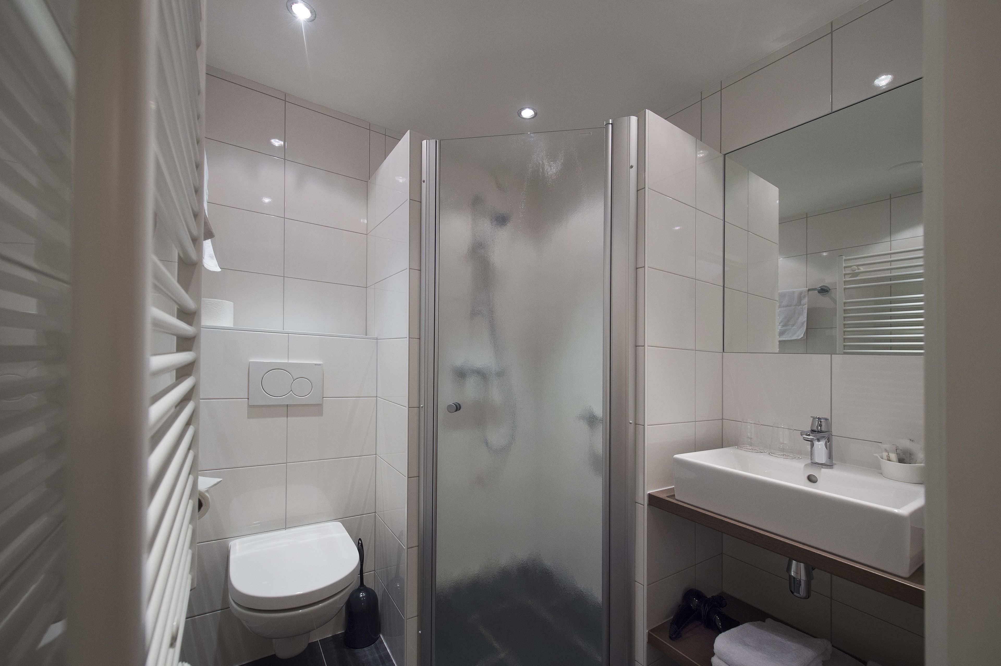 Une salle de bain moderne avec une douche à parois de verre, un lavabo blanc et des toilettes.