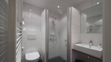 Une salle de bain moderne avec une douche à parois de verre, un lavabo blanc et des toilettes.