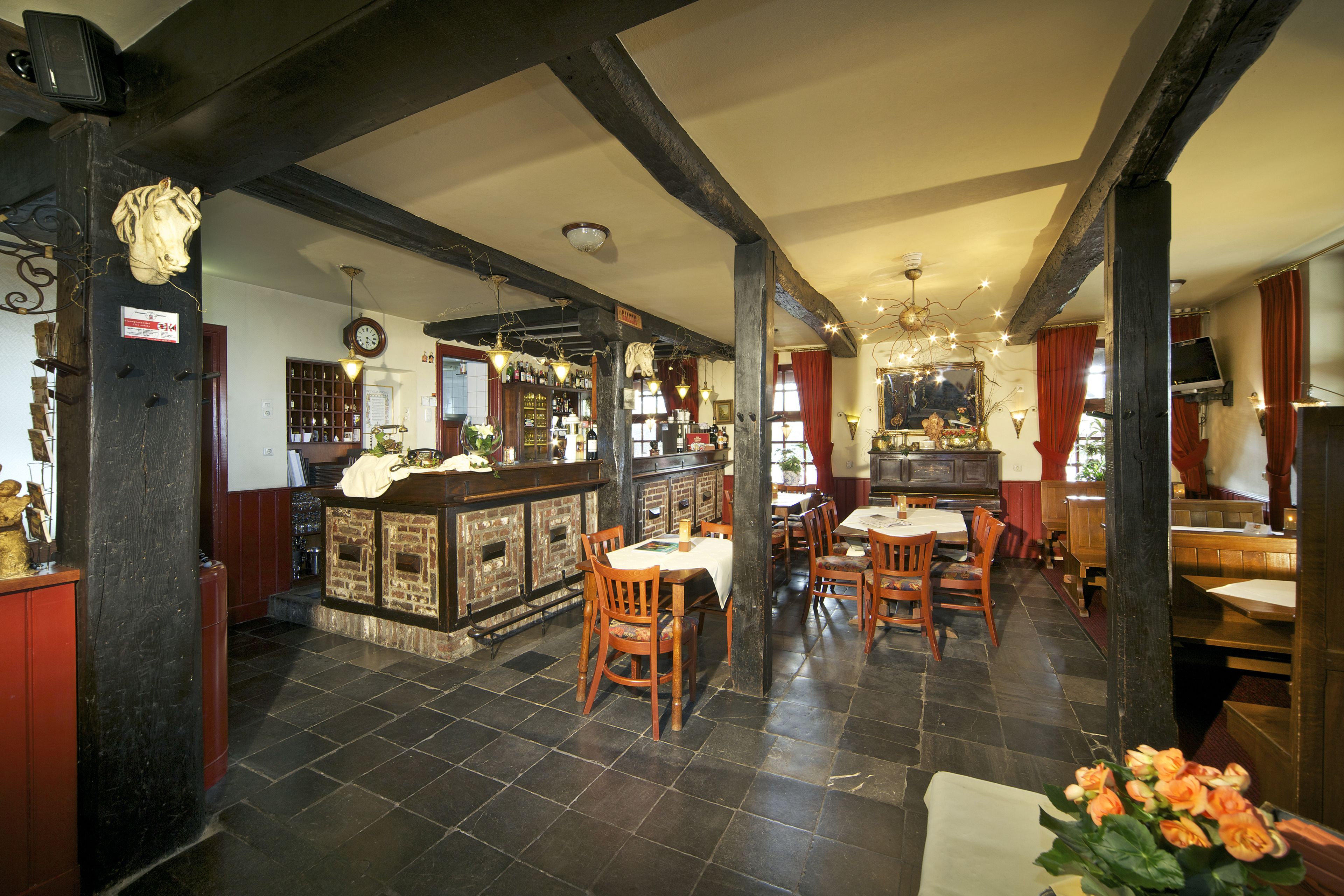 Un restaurant avec des tables et des chaises en bois, un coin bar et une horloge au mur.
