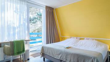 Quarto com cama, cadeira, janela com cortinas e vista para o exterior.